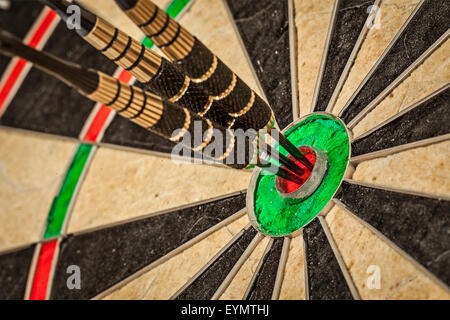 Success hitting target aim goal achievement concept background - three darts in bull's eye close up Stock Photo