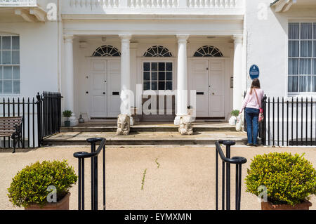 Fortfield terrace in Sidmouth.  A female is examining the blue plaque outside a building where the Grand Duchess Helena lived. Stock Photo