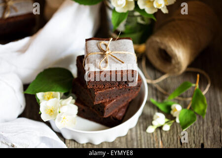 Chocolate mascarpone brownies stacked with flowers on wooden table Stock Photo