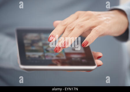 Woman with red manicure using tablet computer. Horizontal photo Stock Photo