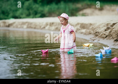 girl plays with paper boats in river Stock Photo