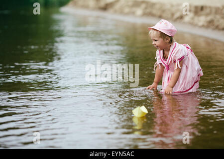 girl plays with paper boats in river Stock Photo