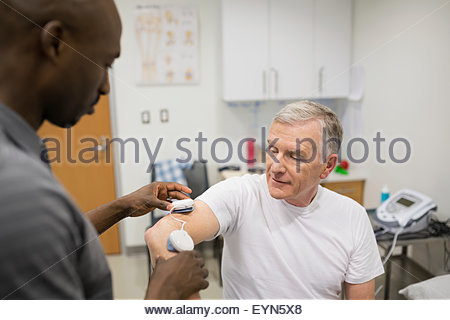 Physical therapist using electrodes on patient arm