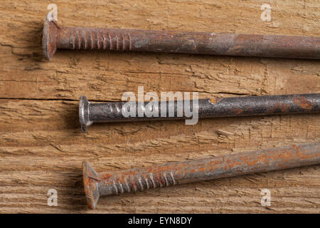 Three rusty nails on wooden board. Stock Photo