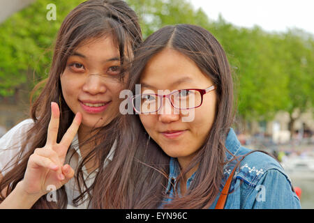 Portrait of two attractive young Asian women, one giving “V” sign Stock Photo