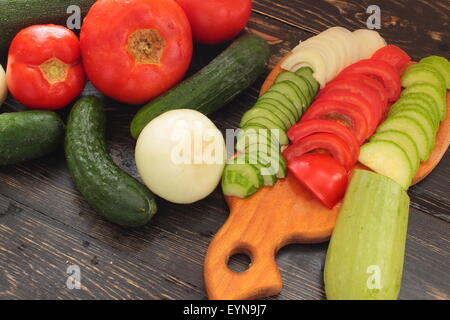 Vegetables on a wooden board as cucumbers, squash, tomatoes, onions Stock Photo