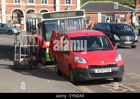 A postman loading a red 2015 Peugeot Royal mail delivery van outside a depot in the small East Sussex town of Rye Stock Photo