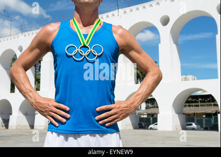 RIO DE JANEIRO, BRAZIL - MARCH 6, 2015: Athlete wearing Olympic rings gold medal stands outdoors in the plaza at Lapa Arches. Stock Photo