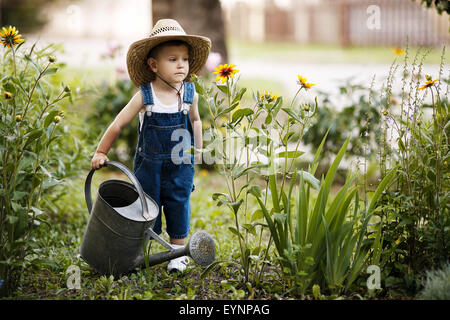 little boy with watering can in summer park Stock Photo