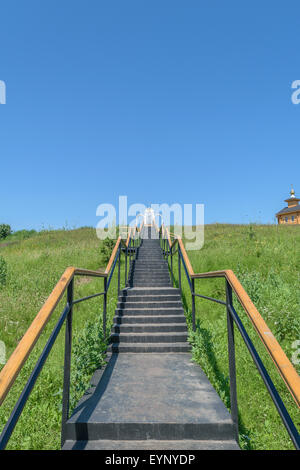 Metal stairs with railings leading up to the place of prayer and a wooden chapel on the hill. Stock Photo