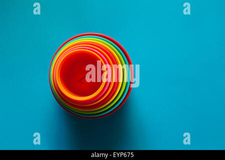 Child's toy stacking cups. Rainbow coloured cups sat on a blue background Stock Photo