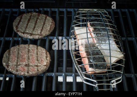 Two hamburger slices and salmon steak on grill rack, soft focus Stock Photo