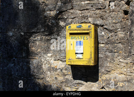 French yellow metal postal (la Poste) letter posting box on stone wall, dappled sunlight Stock Photo