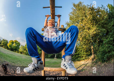 A young boy swings on a climbing frame in a London park Stock Photo