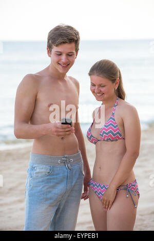 A picture of a young couple using smartphone at the beach Stock Photo