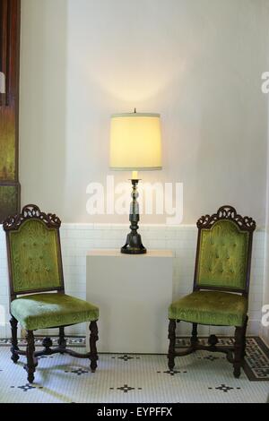 Two green antique chairs with a lamp between them. Stock Photo