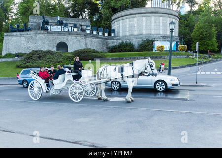 Tourists take a horse drawn carriage ride through the city of Niagara Falls, Ontario Canada Stock Photo
