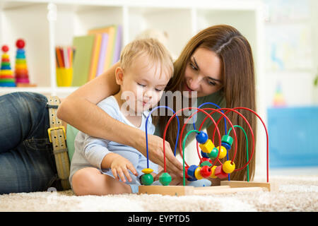 child and mother play with educational toy Stock Photo