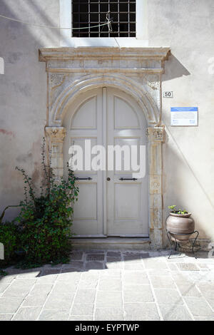 Venetian Traditional arched doorway with delicate but dated and slightly eroded carved stonework, situated in Rethymnon. Stock Photo