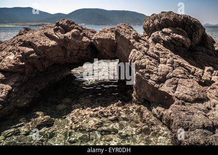 Natural stone grotto on the Mediterranean coast, South Corsica, France. Plage De Capo Di Feno. Dark tonal correction filter effe Stock Photo