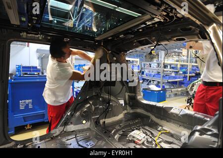 Inside a modern car factory, vehicles and parts move through the production process, fitting wiring loom into the car Stock Photo