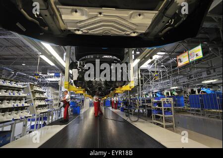 Inside a modern car factory, vehicles and parts move through the production process, under the suspended car bodies Stock Photo