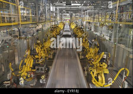 Inside a modern car factory, vehicles and parts move through the production process, robots and car shells blur Stock Photo