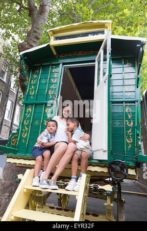 London, UK. 3 August 2015. Sophie Wiles sits with her sons Noah and Joshua in a decorated 'Burton' caravan, circa 1920, refurbished 2015, estimate GBP 25,000-35,000. On 10 September 2015 Christie's South Kensington will hold the third annual 'Out of the Ordinary' auction, celebrating all things extraordiary and unusual - from a massive T-Rex to a portrait of Barack Obama made of toys. The preview marks the start of a free five-week summer exhibition, opening to the public on 3 August 2015. Photo: ukartpics/Alamy Live News Stock Photo