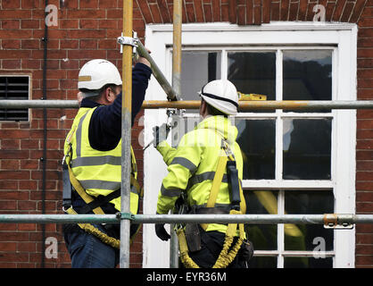 Two workers assembling scaffolding on city building Stock Photo