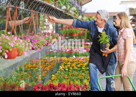 Gardener in front of nursery shop helping woman choosing the right flower Stock Photo