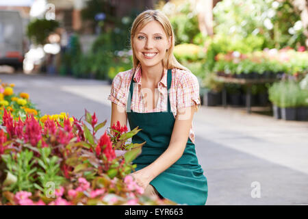Smiling young woman working as gardener in a nursery shop Stock Photo