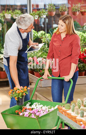 Gardener with tablet PC helping customer choosing the right flowers Stock Photo