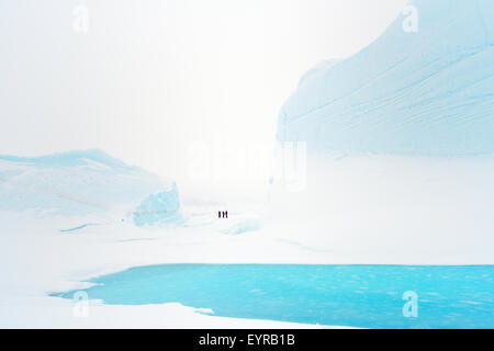 Visitors between in sea ice frozen icebergs, floe edge, Baffin bay, Nunavut, Canada. Stock Photo