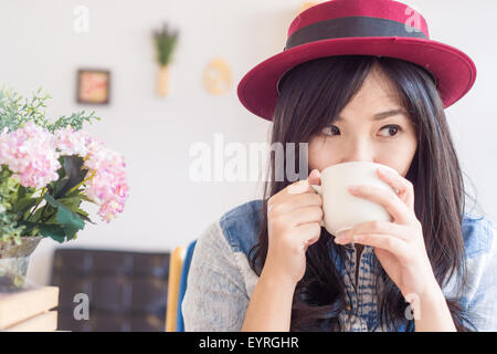 Beautiful asian woman drinking coffee in vintage cafe , Fashionable holding coffee Stock Photo