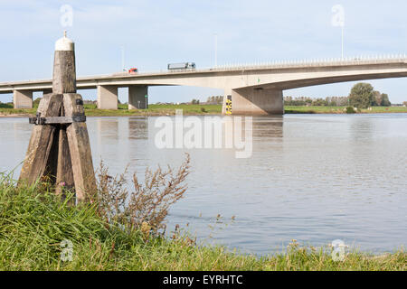 Concrete bridge crossing the river IJssel, the Netherlands, with a wooden bollard in front Stock Photo