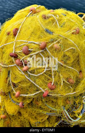 Yellow fishing nets piled up in a Greek Harbour. Stock Photo
