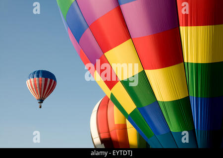 Colorful hot air balloons launching against a blue sky Stock Photo