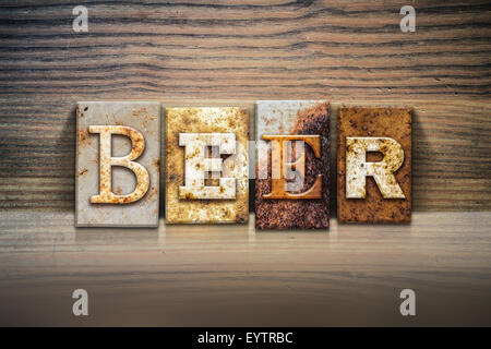 The word 'Beer' written in rusty metal letterpress type sitting on a wooden ledge background. Stock Photo