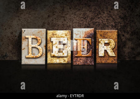 The word 'BEER' written in rusty metal letterpress type on a dark textured grunge background. Stock Photo