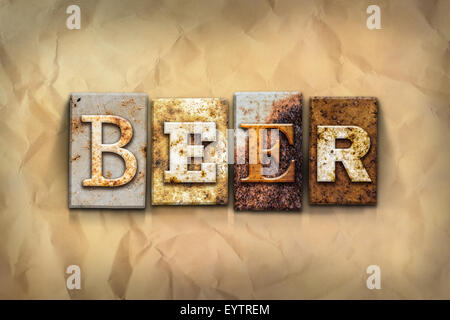 The word 'BEER' written in rusty metal letterpress type on a crumbled aged paper background. Stock Photo