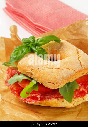 Italian bread roll with thin slices of dry salami Stock Photo