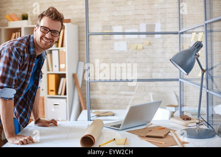 Happy young employee looking at camera in office Stock Photo