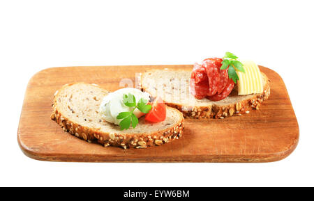 Slices of bread with cheese spread and salami Stock Photo