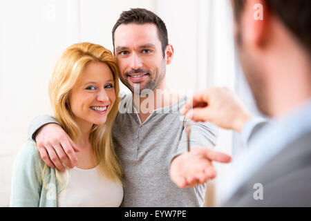 View of Real estate agent delivers keys of new house to young couple Stock Photo