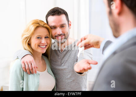 View of Real estate agent delivers keys of new house to young couple Stock Photo