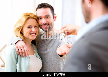 View of Real estate agent delivers keys of new house to young couple Stock Photo