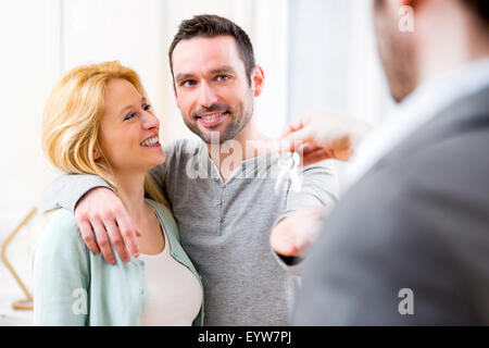 View of Real estate agent delivers keys of new house to young couple Stock Photo