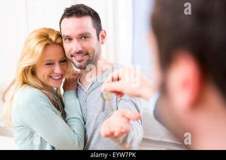 View of Real estate agent delivers keys of new house to young couple Stock Photo