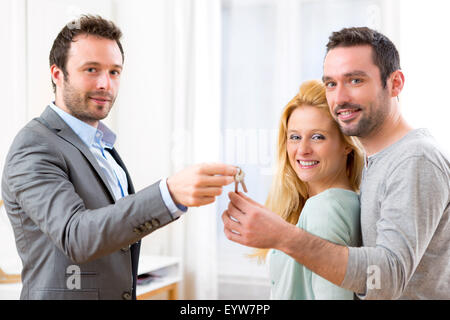 View of Real estate agent delivers keys of new house to young couple Stock Photo