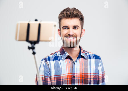 Portrait of a cheerful young man making selfie photo with stick isolated on a white background Stock Photo